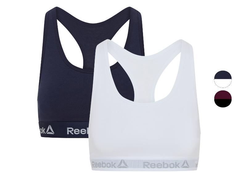 Twee Reebok sportbeha's, één donkerblauw en één wit, met elastische band.