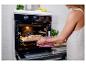 Vrouw haalt versgebakken brood uit een moderne oven met digitaal display.