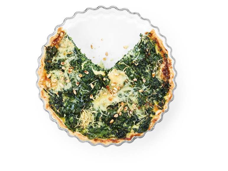 Een gedeeltelijk gegeten spinaziequiche met pijnboompitten.