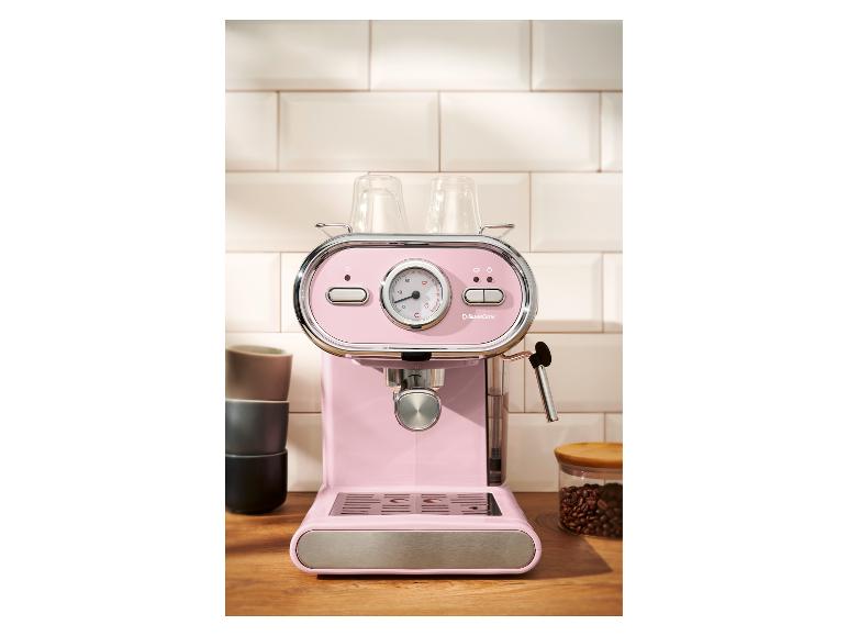 Roze espressomachine met kopjes en koffiebonen op een houten aanrecht.