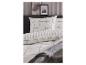 Bed met wit beddengoed met grijs geruit patroon en kussens, met schilderijen aan de muur.