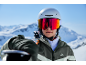 Skiër met helm en skibril, met ski's op een besneeuwde berg.