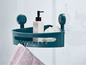 Een groene hoekplank met zuignappen in een douche, met shampoo, een spons en een handdoek.