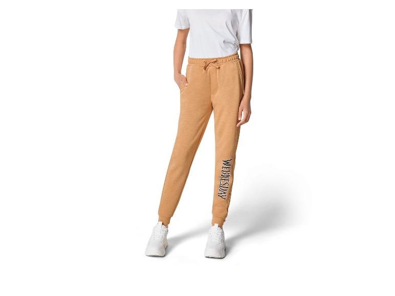 Beige joggingbroek met 'Wednesday' logo en witte sneakers.
