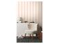 Woonkamer met gestreept behang, wit dressoir, pluizige fauteuil en donkergrijs vloerkleed.