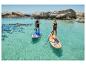 Twee personen op paddleboards in turquoise water met rotsen op de achtergrond.