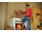 Man in kersttrui versiert de kamer met een accuschroevendraaier in zijn hand.
