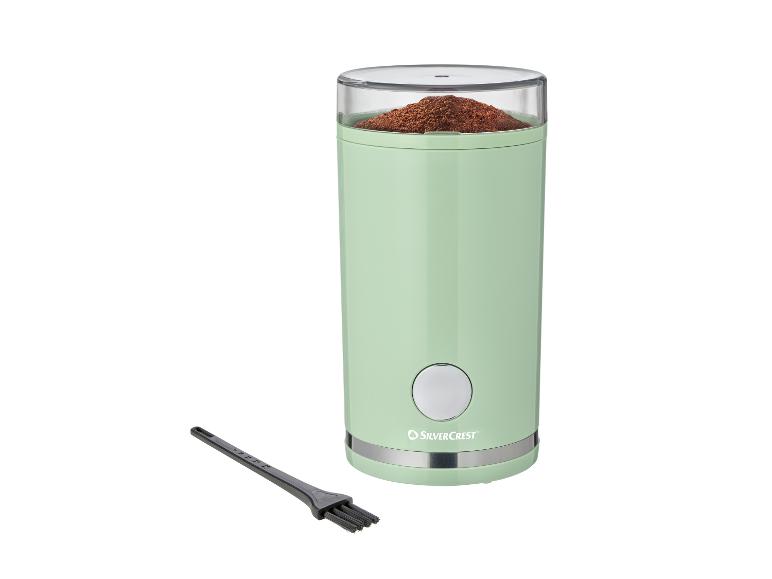 Mintgroene elektrische koffiemolen met gemalen koffie en schoonmaakborsteltje