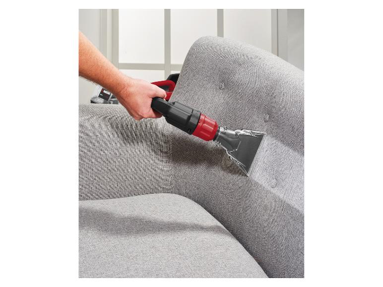 Man reinigt een grijze bank met een bekledingsreiniger.