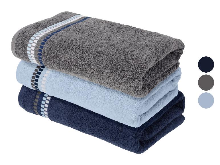 Gestapelde handdoeken in grijs, lichtblauw en donkerblauw met decoratieve strepen.