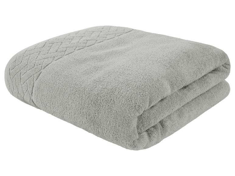 Een grijze badhanddoek gevouwen op een witte achtergrond.