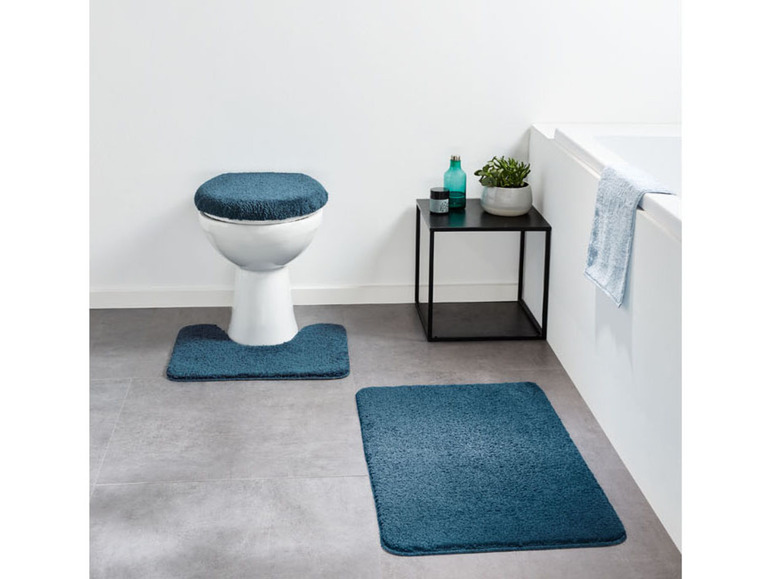 Badkamerset met een donkerblauwe toiletbril en twee badmatten.