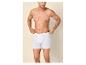 Man zonder shirt in witte boxershorts, die de tailleband aanpast.