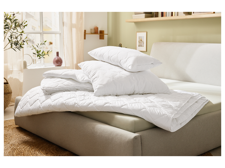 Wit katoenen beddengoed met dekbed en kussens.