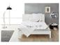 Wit bed met gewatteerd dekbed en kussens, moderne lamp en decoratieve plank in een slaapkamer.