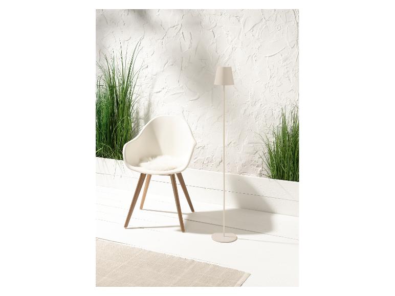 Wit design stoel, staande lamp en groene planten in een minimalistische setting.