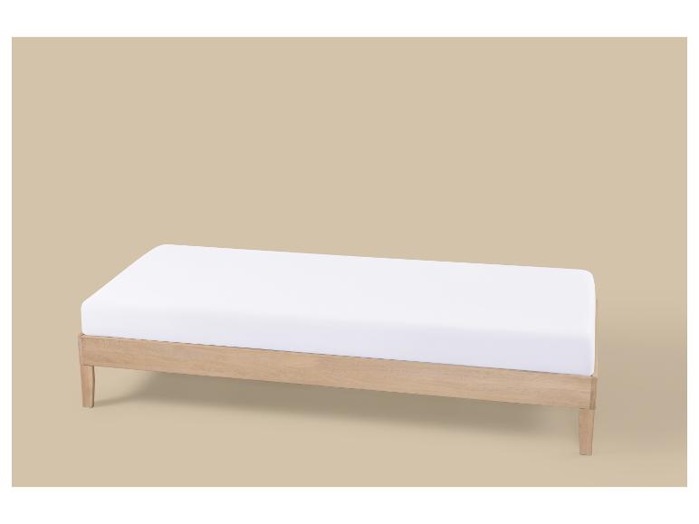 Licht houten eenpersoonsbed met wit matras op een beige achtergrond.
