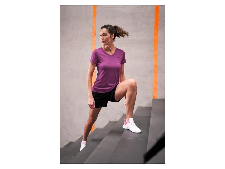 Vrouw in paars sportshirt en zwarte shorts oefent op de trap.
