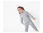 Een jong meisje draagt een grijze hoodie en joggingbroek.