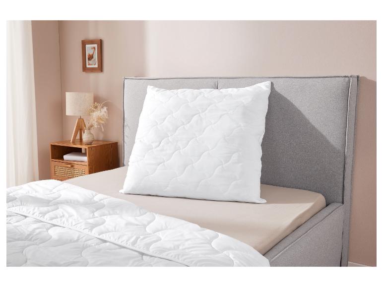 Wit gewatteerd kussen en dekbed op een bed.