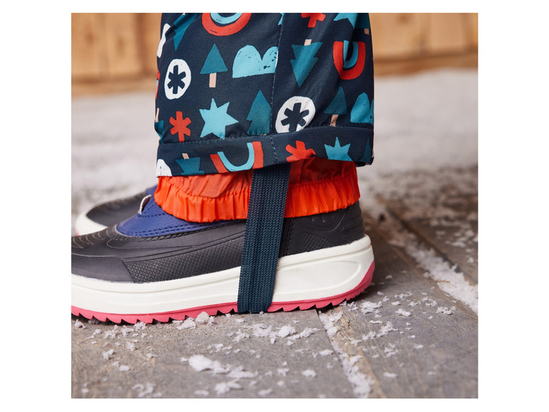Een kinderschoen met een regenbroek met een vrolijk printje.