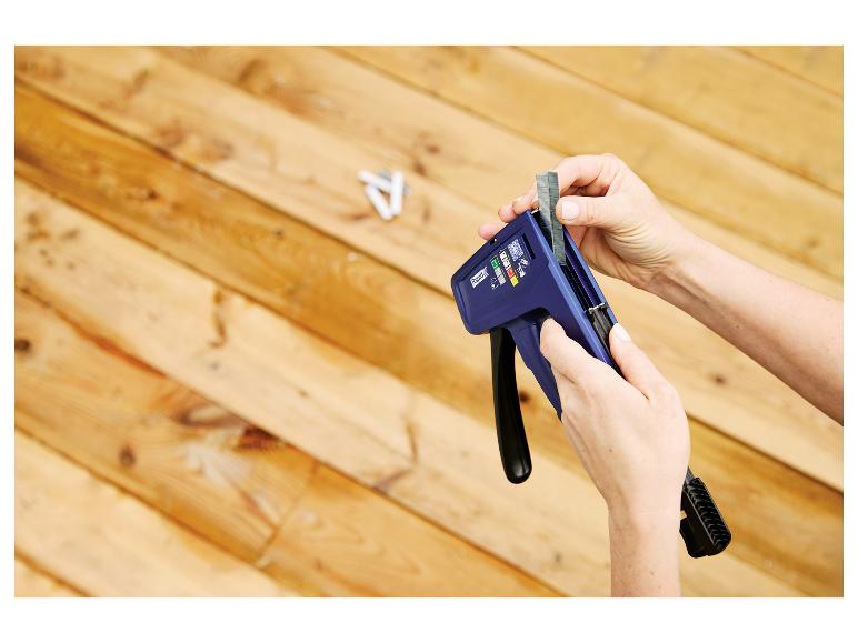 Persoon laadt LIVARNO® Handtacker »RPC7« met nietjes tegen een houten achtergrond.