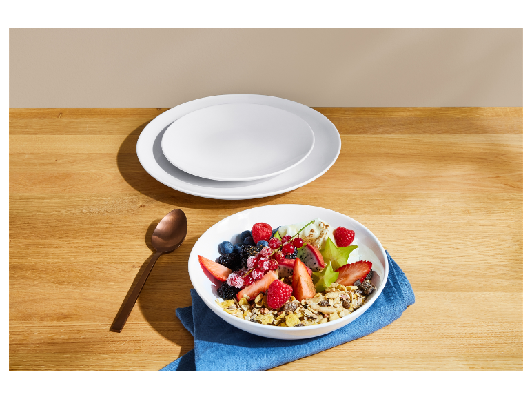 Een kom muesli met vers fruit op een houten tafel.