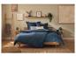 Slaapkamer met houten bed, blauw beddengoed, nachtkastjes en wanddecoraties.