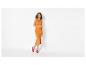 Vrouw in een oranje mouwloze midi-jurk en roze sandalen met hak.