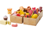 Houten speelgoedvoedselset met fruit, groenten, brood, kaas en vlees in kratten.
