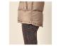 Close-up van een persoon in een beige puffer bodywarmer en donkere jeans.