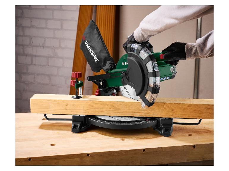 Man zaagt een houten plank met een afkortzaag op een werkbank.