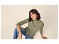 Vrouw in olijfgroene ribgebreide trui en blauwe jeans, zittend op de grond.