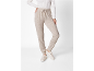 Vrouw in beige joggingbroek en witte trui, met lichte sneakers.