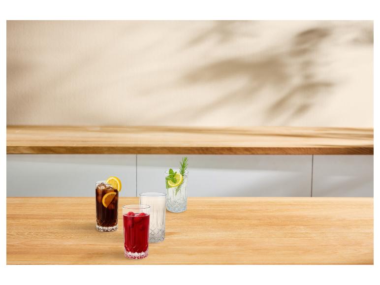 Drie glazen verfrissende drankjes en een leeg glas op een houten aanrecht.