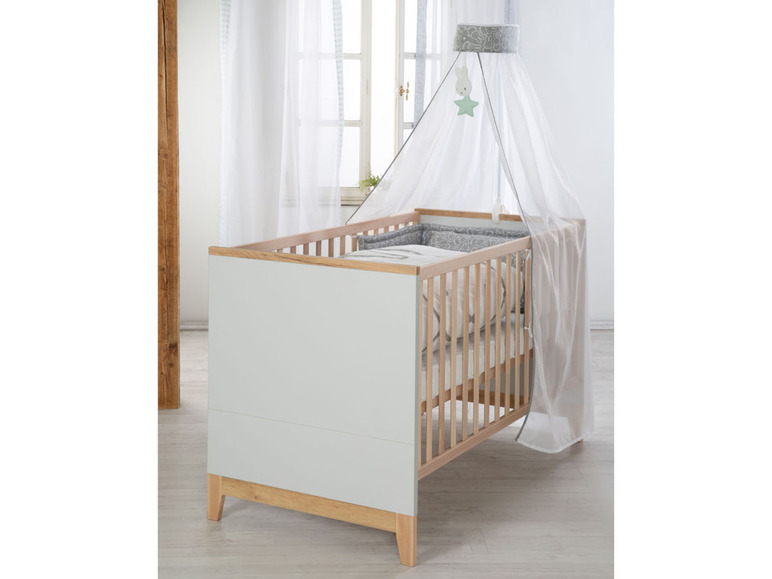 Een babybed met een wit muskietennet en een grijze print.