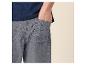 Man in blauw T-shirt en grijze korte broek met hand in zak.