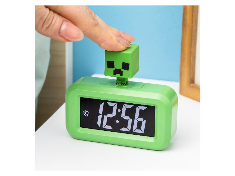Groene Minecraft Creeper wekker met een hand die de bovenkant indrukt