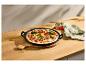 Groentepizza in een zwarte gietijzeren pan op een houten tafel met een linnen doek.