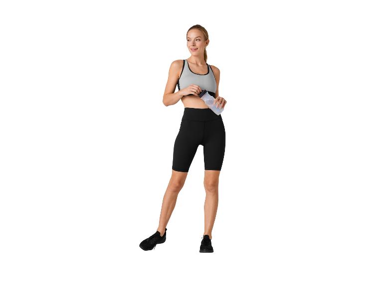 Vrouw in sportkleding: top, fietsbroek en waterfles.