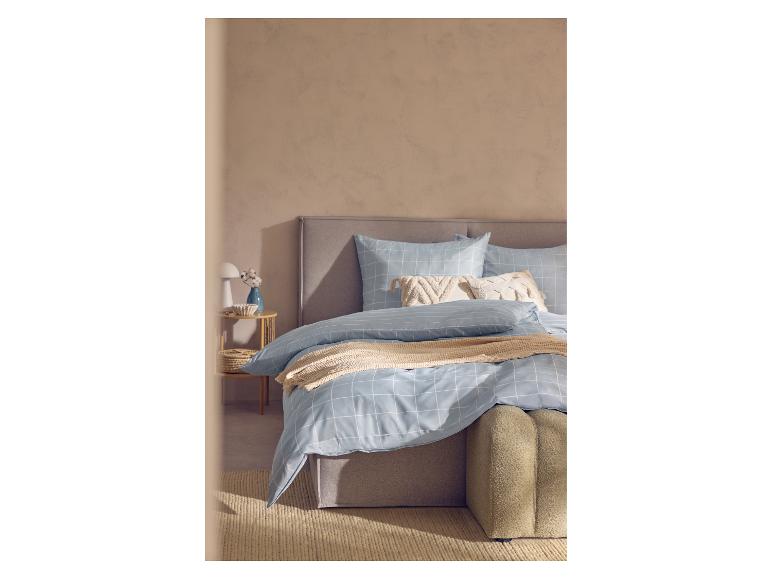 Slaapkamer met een bed met blauw-wit geruit beddengoed, een beige plaid en decoratieve kussens.