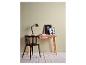 Een modern houten bureau met een zwarte stoel, een zwarte bureaulamp en twee ingelijste foto's.