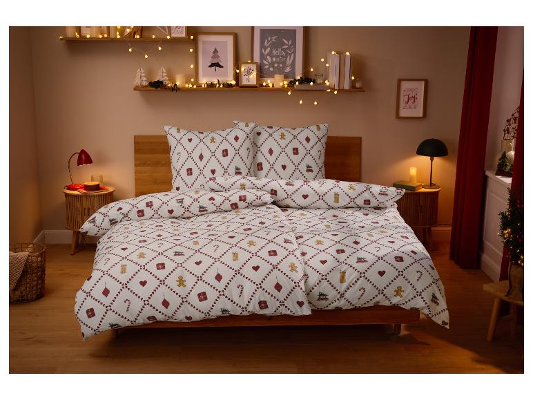 Kerstversierde slaapkamer met feestelijk beddengoed en lichtslingers.