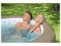 Koppel ontspant in een buitenjacuzzi omringd door groen.