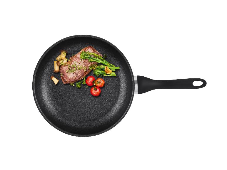 Een zwarte koekenpan met een gebakken biefstuk, champignons, broccoli en cherrytomaatjes.