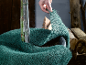 Hand wikkelt groen jute om een jonge boom ter winterbescherming.