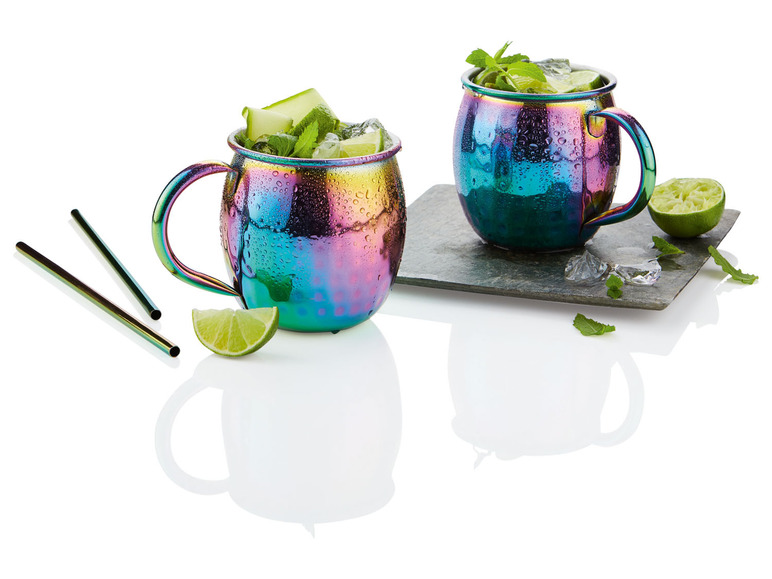 Twee regenboogkleurige koperen Moscow Mule bekers met limoen en munt.