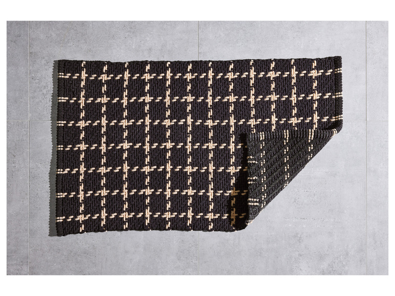 Een zwart-wit gestreept vloerkleed met een geometrisch patroon.