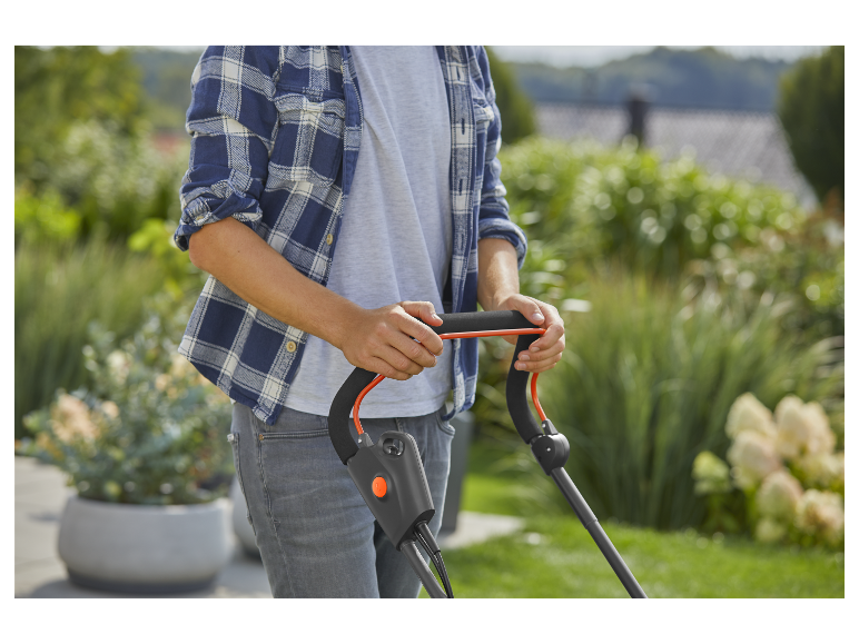 Een man gebruikt een grasmaaier in de tuin.