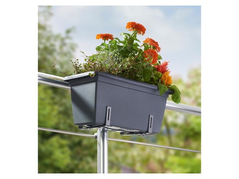 Grijze balkonbak met oranje bloemen en groene planten, gemonteerd aan een reling.